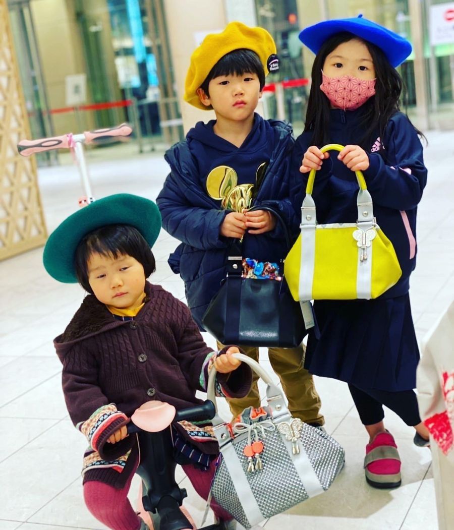 Trois enfants tenant des sacs Comme les Papillons dans un centre commercial japonais